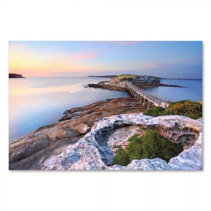 Atemberaubender Sonnenaufgang über einer Insel, die durch eine malerische Holz Brücke mit dem Festland verbunden ist.